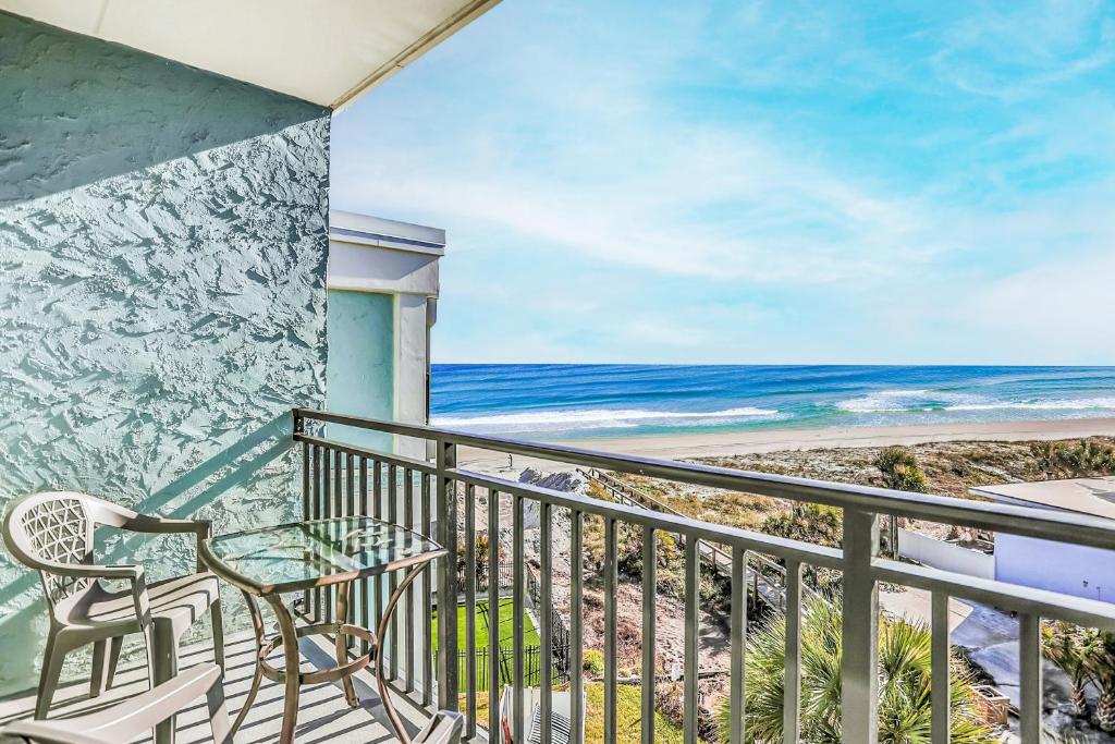 a balcony with a table and chairs and the ocean at Sunshine and a View in Jacksonville Beach