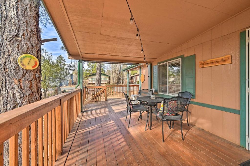 un porche con mesa, sillas y un árbol en Munds Park Cabin with Wraparound Deck and Grill!, en Munds Park