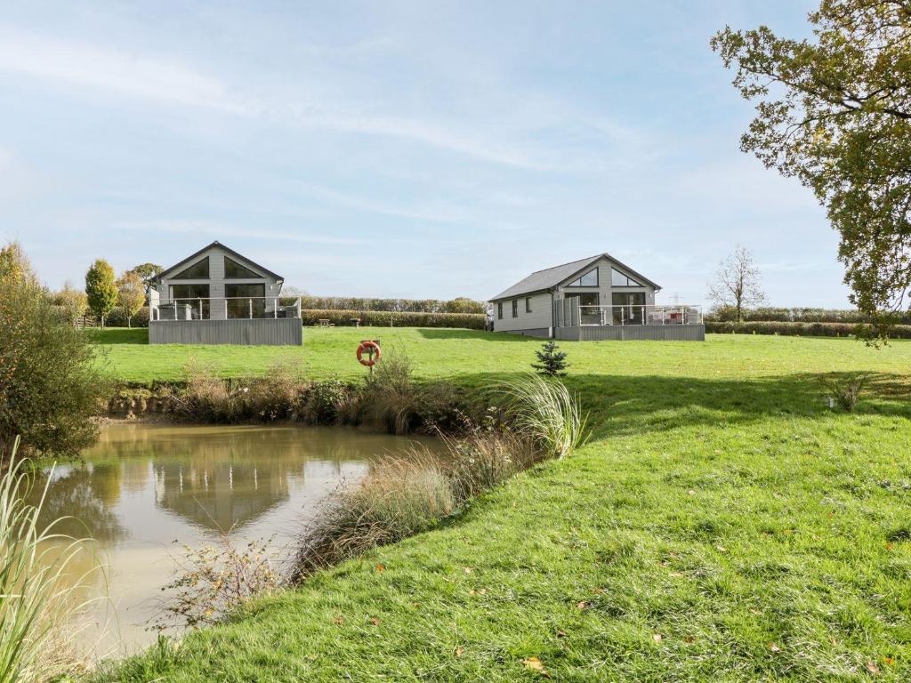 zwei Häuser auf einem Feld mit einem Teich in der Unterkunft 2 Oak Park in Tiverton