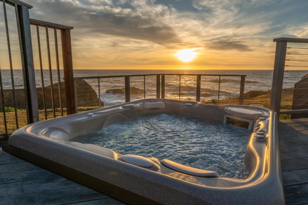 a hot tub on a deck with a view of the ocean at Spectacular Oceanfront Studio with Hot Tub & Loft in Fort Bragg