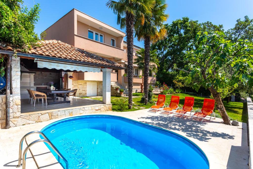 a swimming pool in front of a house at Apartmani Gabi in Njivice