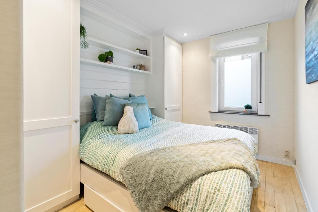 een slaapkamer met een bed met blauwe kussens en een raam bij Appartement SUB in Oostende in Oostende