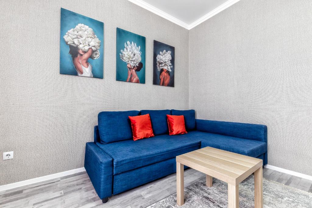 eine blaue Couch in einem Wohnzimmer mit Gemälden an der Wand in der Unterkunft Комфортная квартира в центре города in Astana