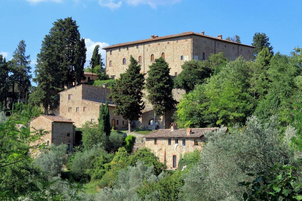 um grande edifício de tijolos no meio de uma floresta em Castello di Bibbione em San Casciano in Val di Pesa