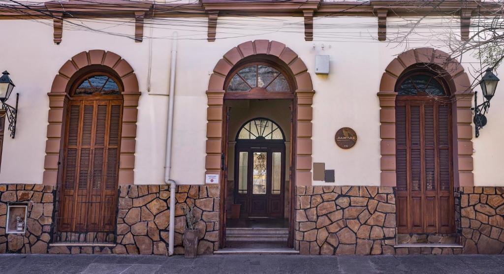 ein Gebäude mit drei Türen und einer Steinmauer in der Unterkunft HOSTEL PUNTO RAMIREZ in Salta