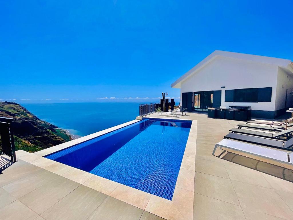 a villa with a swimming pool in front of the ocean at Villa Camacho xxvii in Arco da Calheta