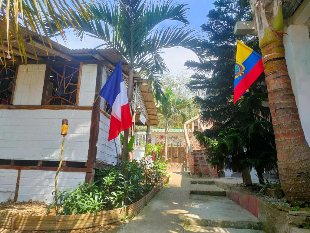 duas bandeiras numa casa com uma palmeira em Munay Backpacker Hostel em Montañita