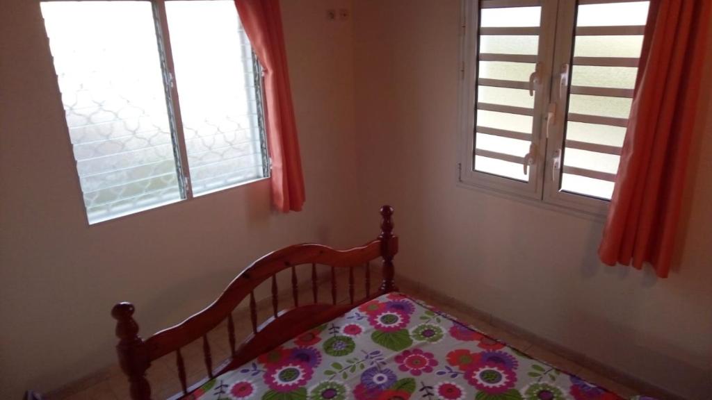 a bedroom with a crib and two windows at Mandévilla et Tropical Dream in Les Trois-Îlets