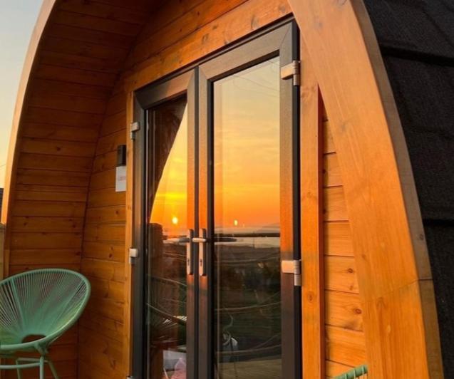 Cette chambre dispose d'une fenêtre offrant une vue sur le coucher du soleil. dans l'établissement The Sleepy Crofter Glamping - Achiltibuie, à Achiltibuie