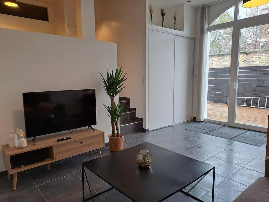 ein Wohnzimmer mit einem Flachbild-TV und einem Tisch in der Unterkunft Bel Appartement Grande Terrasse avec parking à Dijon in Dijon