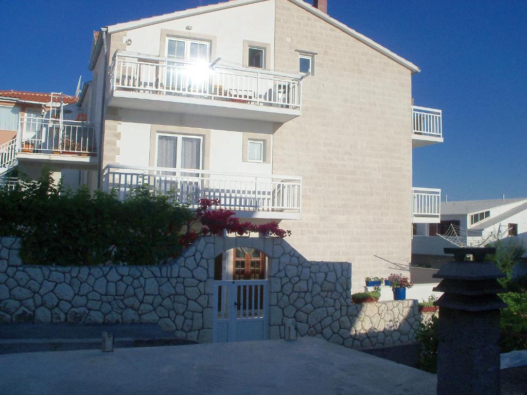 a large white building with a stone wall at Apartments Radonic in Hvar
