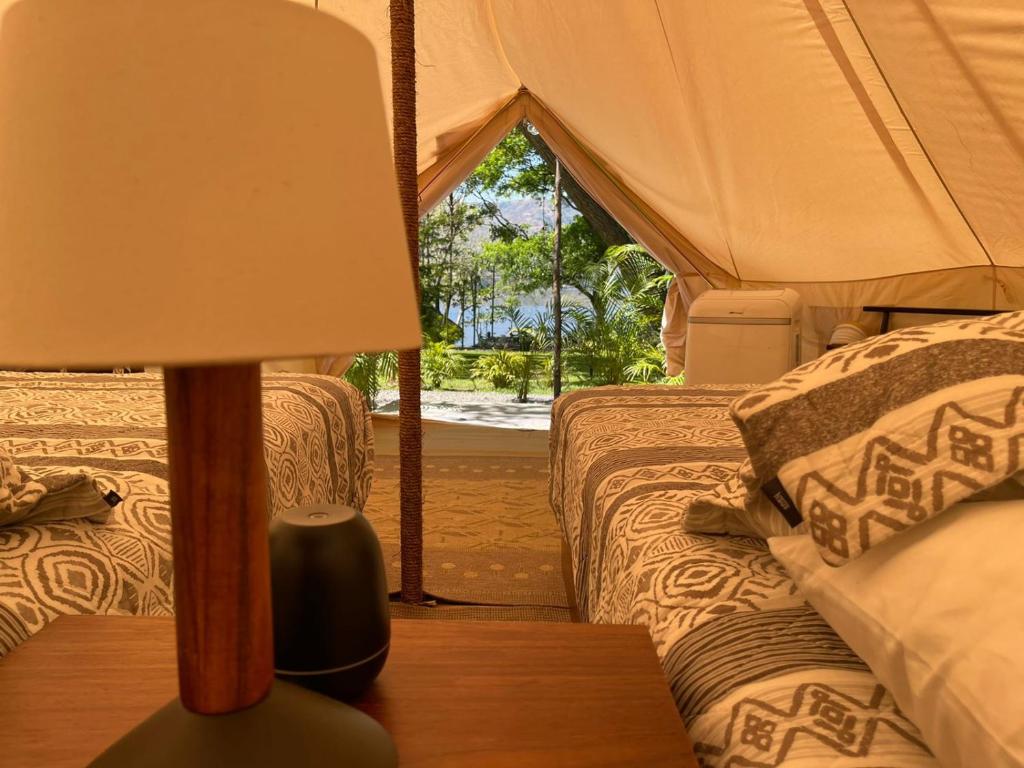 a lamp on a table next to two beds in a tent at Punta Santa Maria in Santa María del Oro