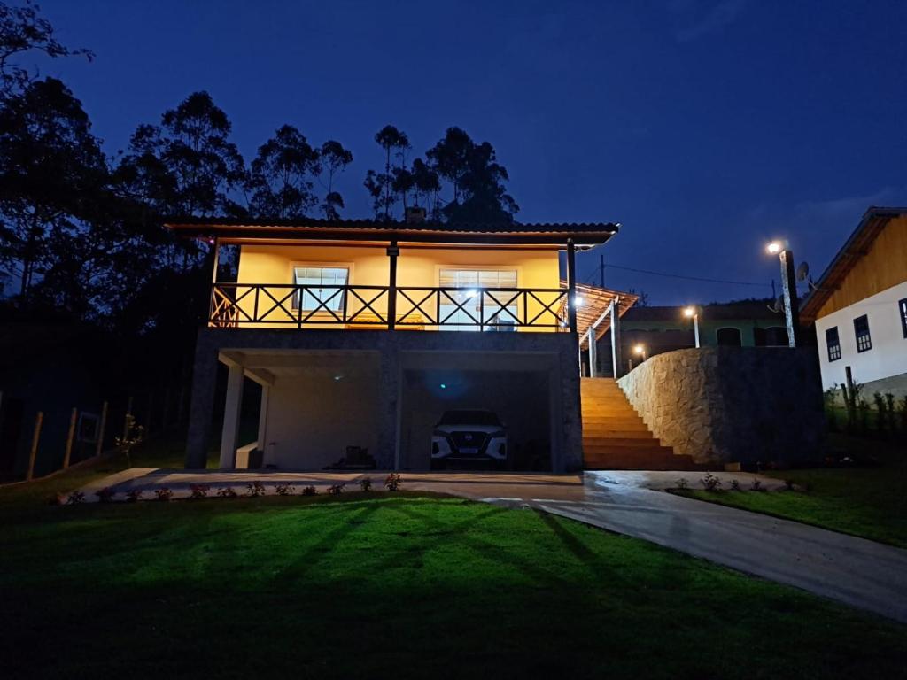 a house lit up at night with a yard at A Casa do Júnior em Visconde de Mauá in Visconde De Maua