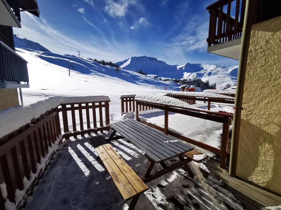 un banc en bois assis sur une terrasse couverte dans la neige dans l'établissement Appartement ski au pied 5-6 personnes La plagne tarentaise, à Plagne Villages