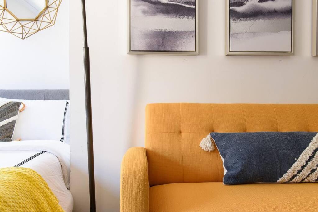 24-16 Studio Gramercy W D gramercy في نيويورك: أريكة صفراء في غرفة النوم مع صور على الحائط