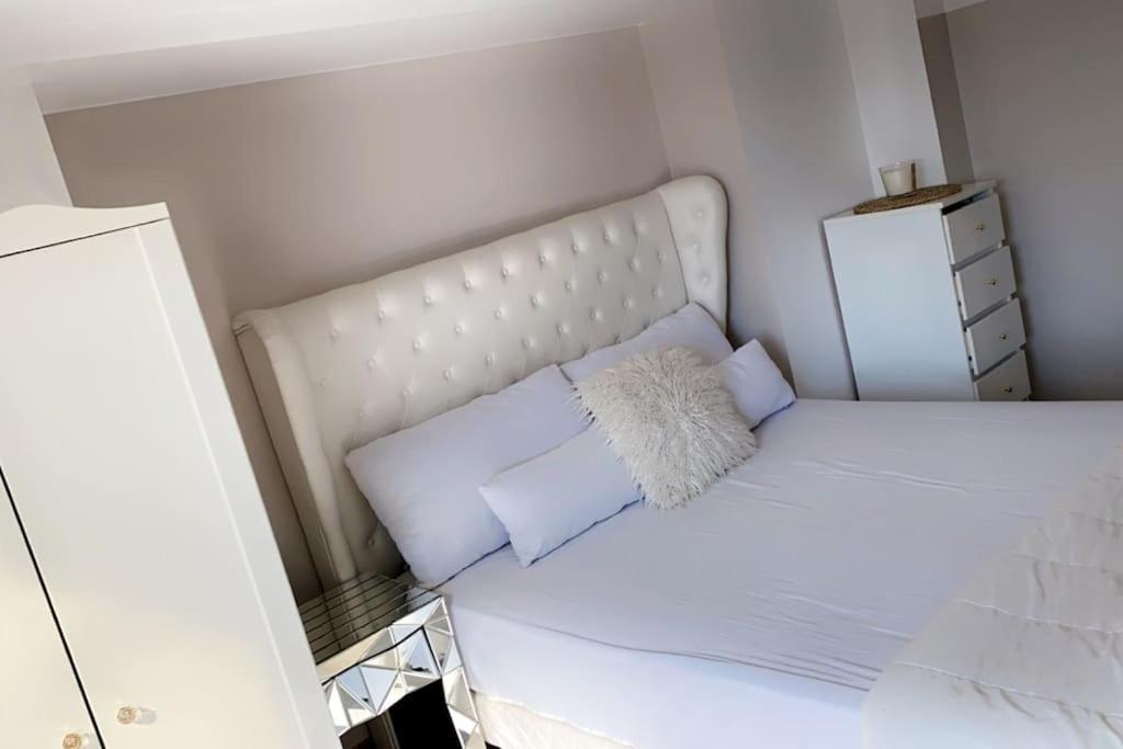 um pequeno quarto com uma cama branca e 2 almofadas em CLICHY SOUS BOIS APPARTEMENT RÉCENT & CHALEUREUX em Clichy-sous-Bois