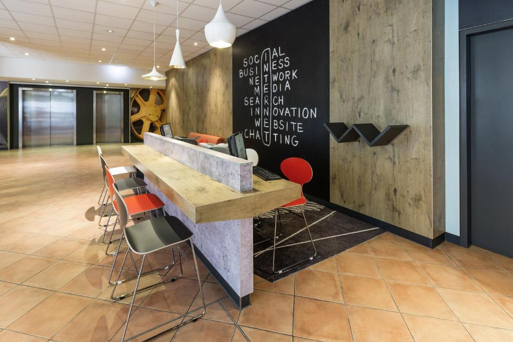 a lobby with a desk and chairs in a room at ibis München Parkstadt Schwabing in Munich