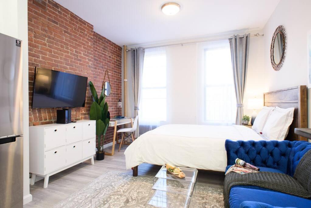 a bedroom with a bed and a brick wall at 240-5 NEW Prime Location STUDIO W&D in unit in New York