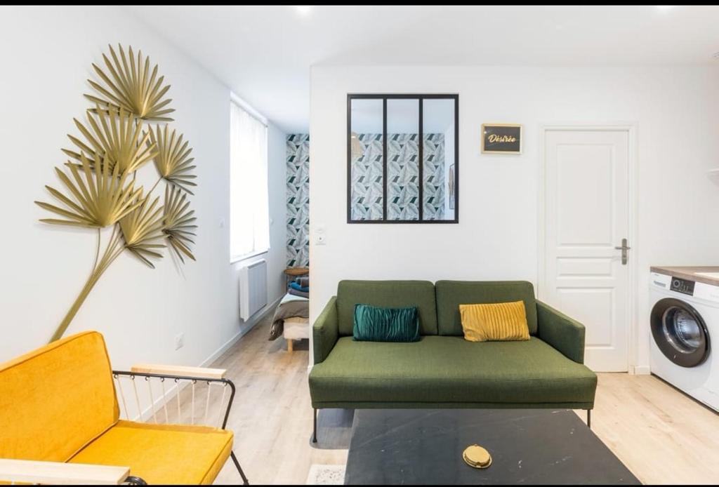 a living room with a green couch and a palm tree at Désirée Logement Cosy et Charmant 1 er étage in Reims