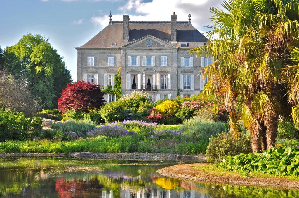 une maison ancienne avec un jardin en face d'un lac dans l'établissement Chateau de la Foltière, à Le Châtellier