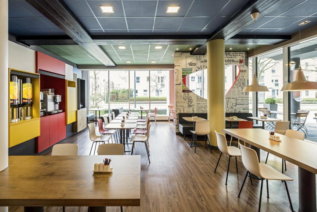 a restaurant with tables and chairs and a cafeteria at ibis München Parkstadt Schwabing in Munich