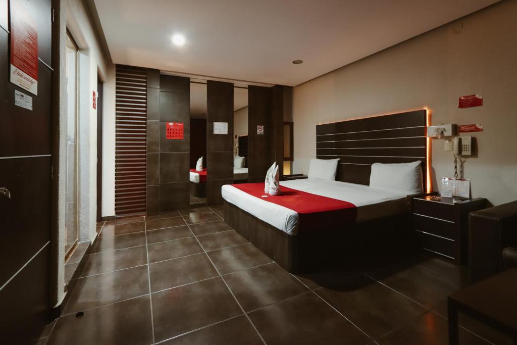 a bedroom with a large bed with a red blanket at Auto Hotel Las Maravillas in Santa Cruz Xoxocotlán