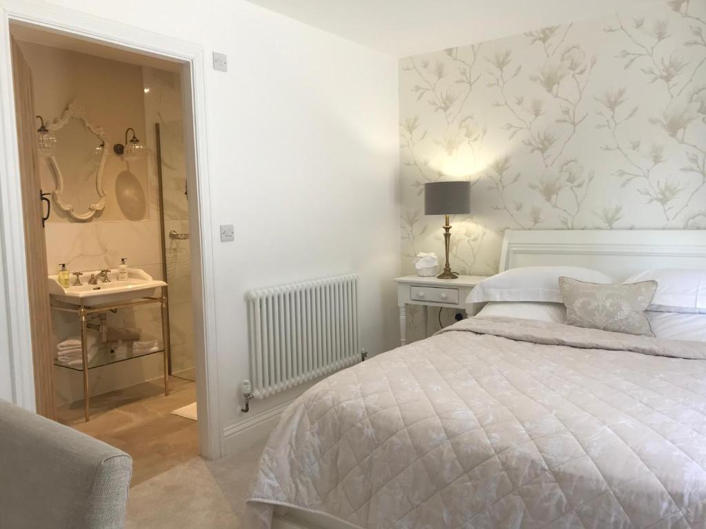 a bedroom with a bed and a bathroom with a sink at Abbey Green Farm in Wem