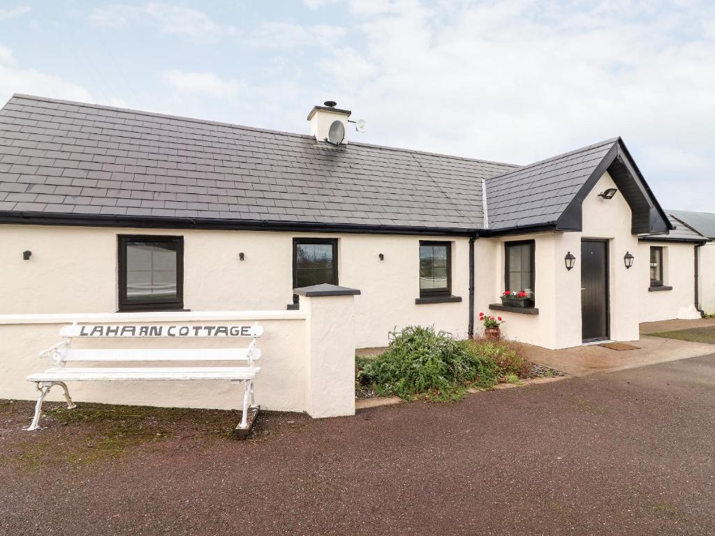 un bâtiment blanc avec un banc devant lui dans l'établissement Laharn Cottage, à Killorglin