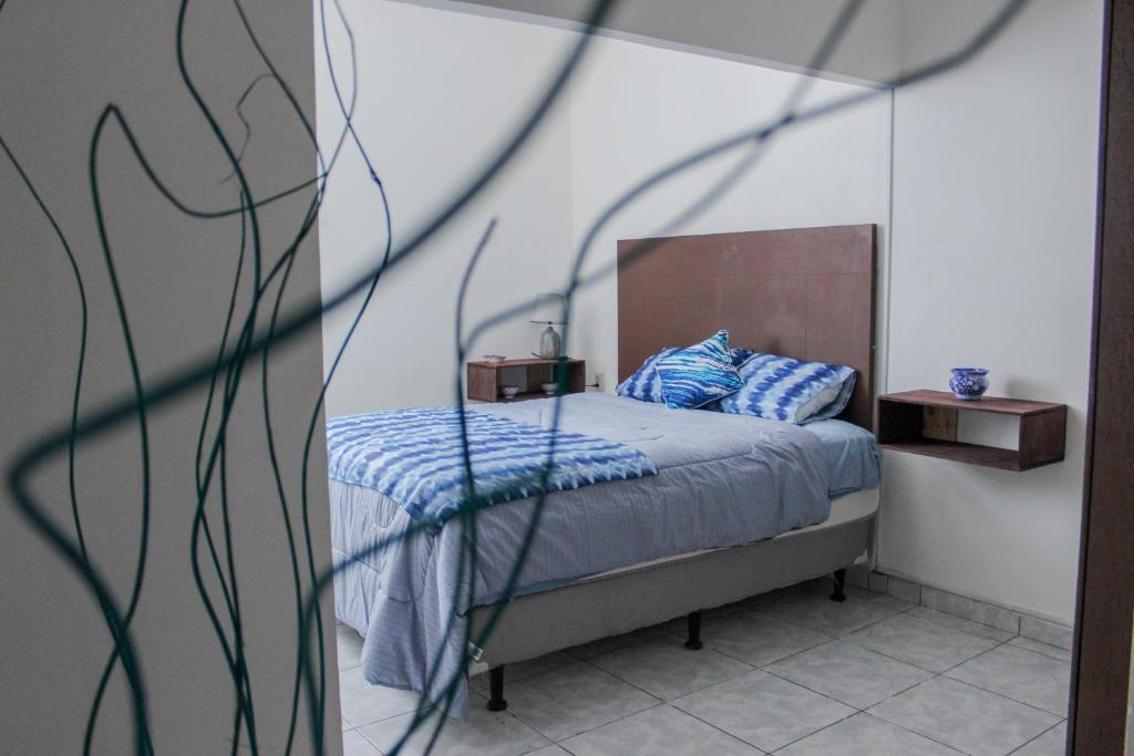 a bedroom with a bed with blue sheets and a mirror at Hotel y Café Ixmati Suchitoto in Suchitoto