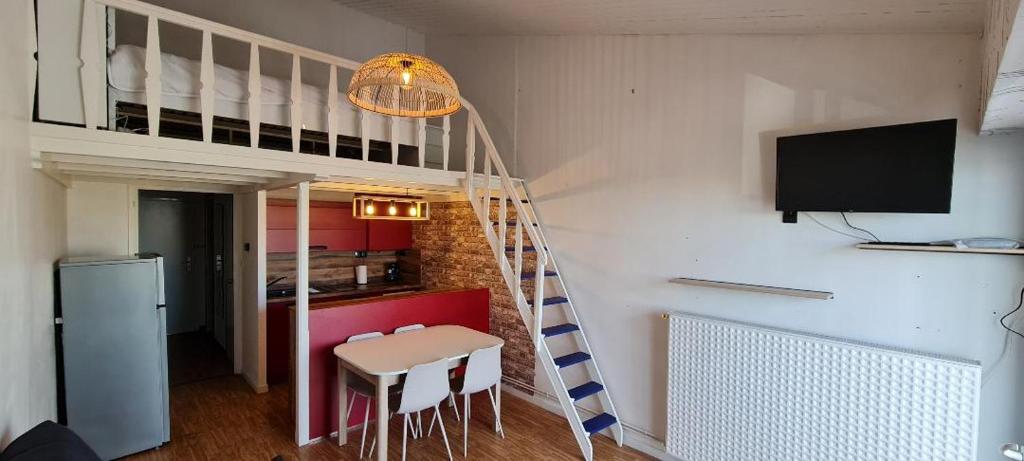 une chambre avec un escalier, une table et des chaises dans l'établissement Studio vue sur mer, à La Chaume