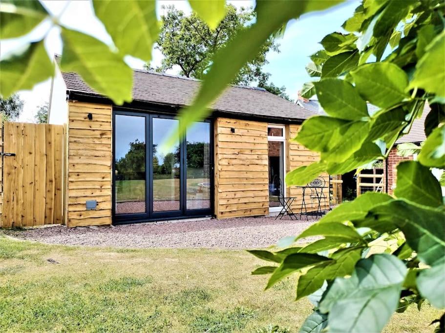 a wooden cabin with glass doors on a yard at The Garden Room - Nature Stay in Suckley