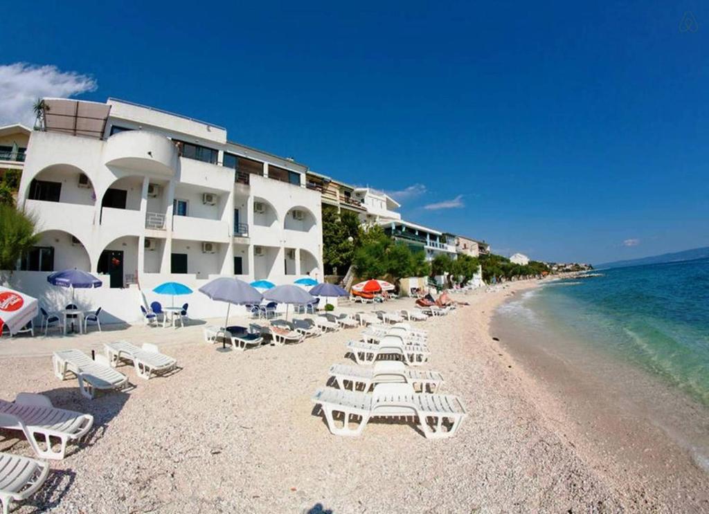 una playa con sillas y sombrillas y el océano en Villa Tamaris on the beach, en Podstrana