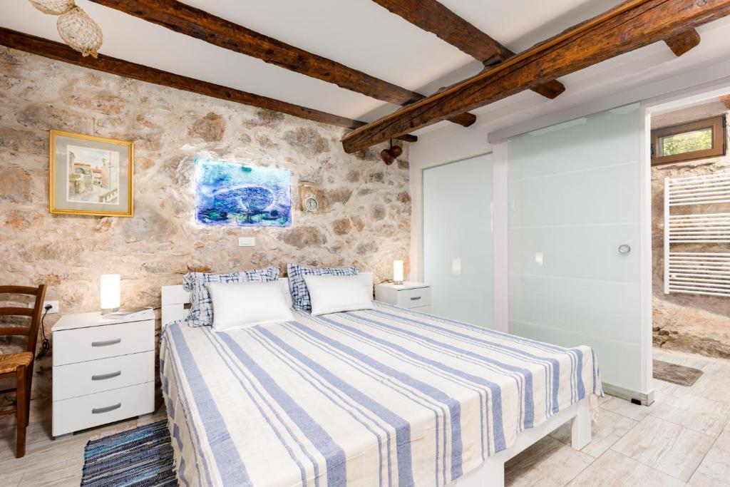 a bedroom with a large bed and a stone wall at Apartment VOLTE in Punat