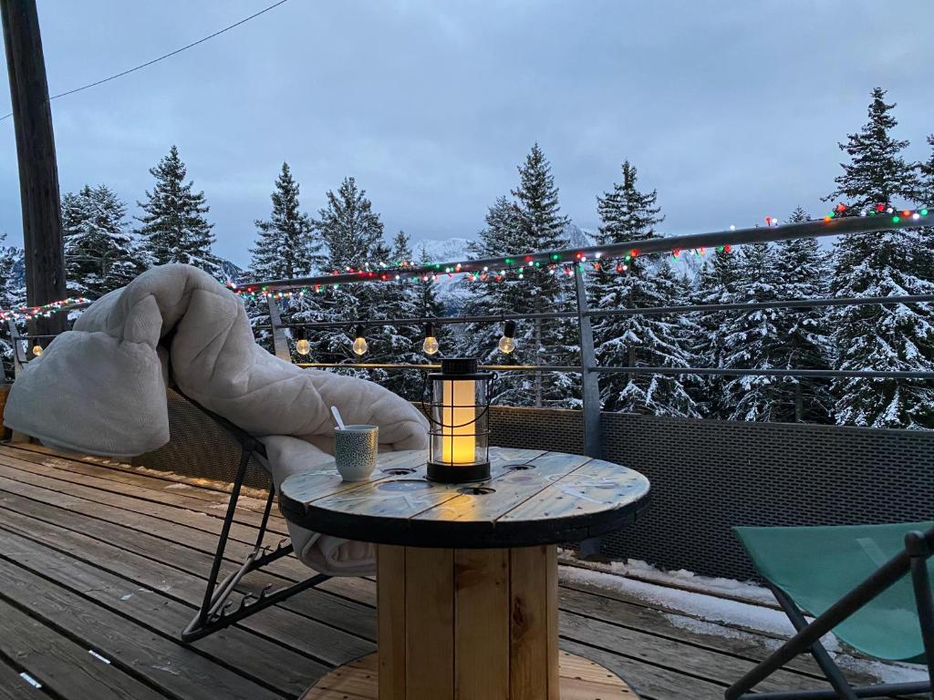 una mesa con una vela en una terraza con luces de Navidad en Mélèze B *** plein Sud, en Chamrousse