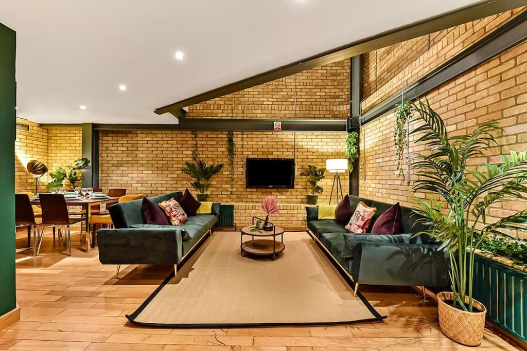 a living room with couches and a brick wall at Spacious 2 Bed Urban Jungle Flat, Central London in London