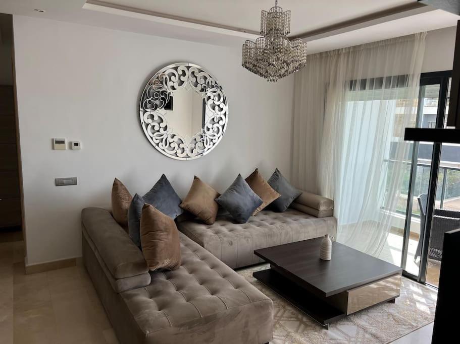 uma sala de estar com um sofá e um espelho em Superbe appartement avec piscine em Rabat