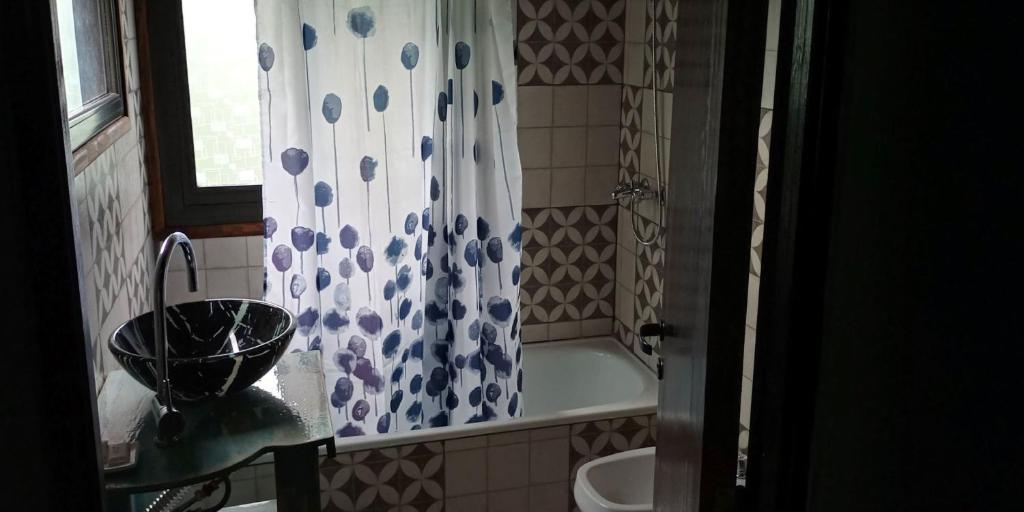 y baño con cortina de ducha, bañera y lavamanos. en La Eugenia en Sierra de los Padres