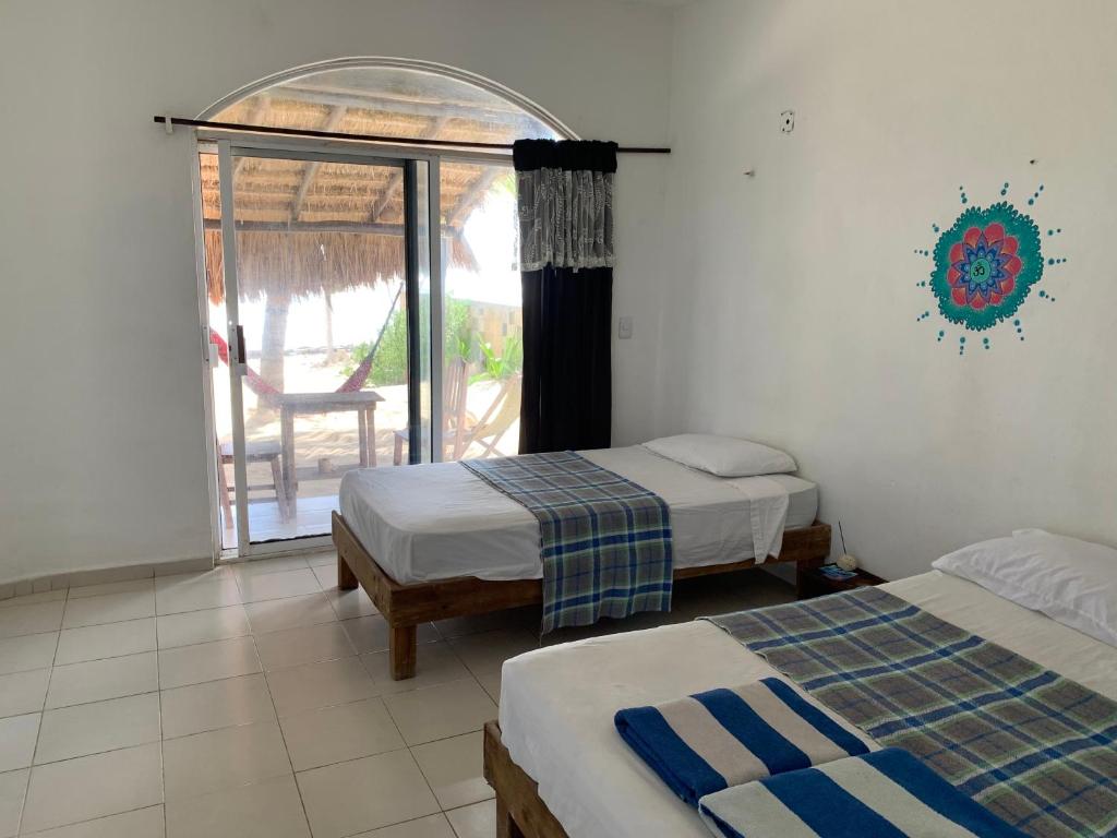 a room with two beds and a window with a patio at Casa Kayab in Puerto Morelos