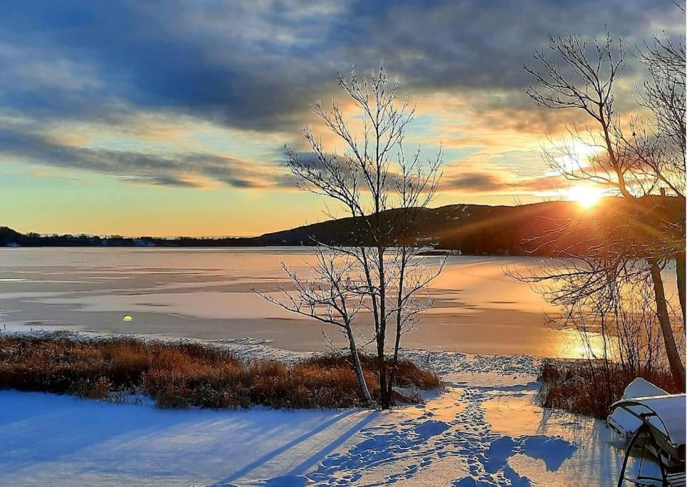 a sunset over a body of water with snow on the ground at Nouveau * Bord de lac * spa, foyer, Netflix et + in Hébertville