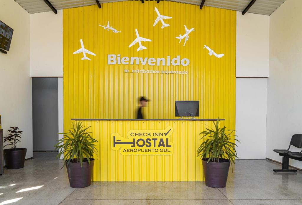uma parede amarela com aviões sobre ela em um aeroporto em CHECK INN HOSTAL AEROPUERTO GDL em Guadalajara
