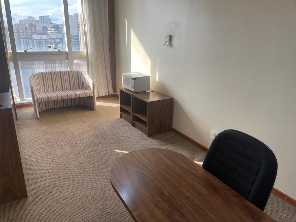 a room with a table and a tv and a chair at PROMOÇÃO EXECUTIVA COM BANHEIRA E FLATS SEM BANHEIRA- Melhor Hotel De Taguatinga in Taguatinga