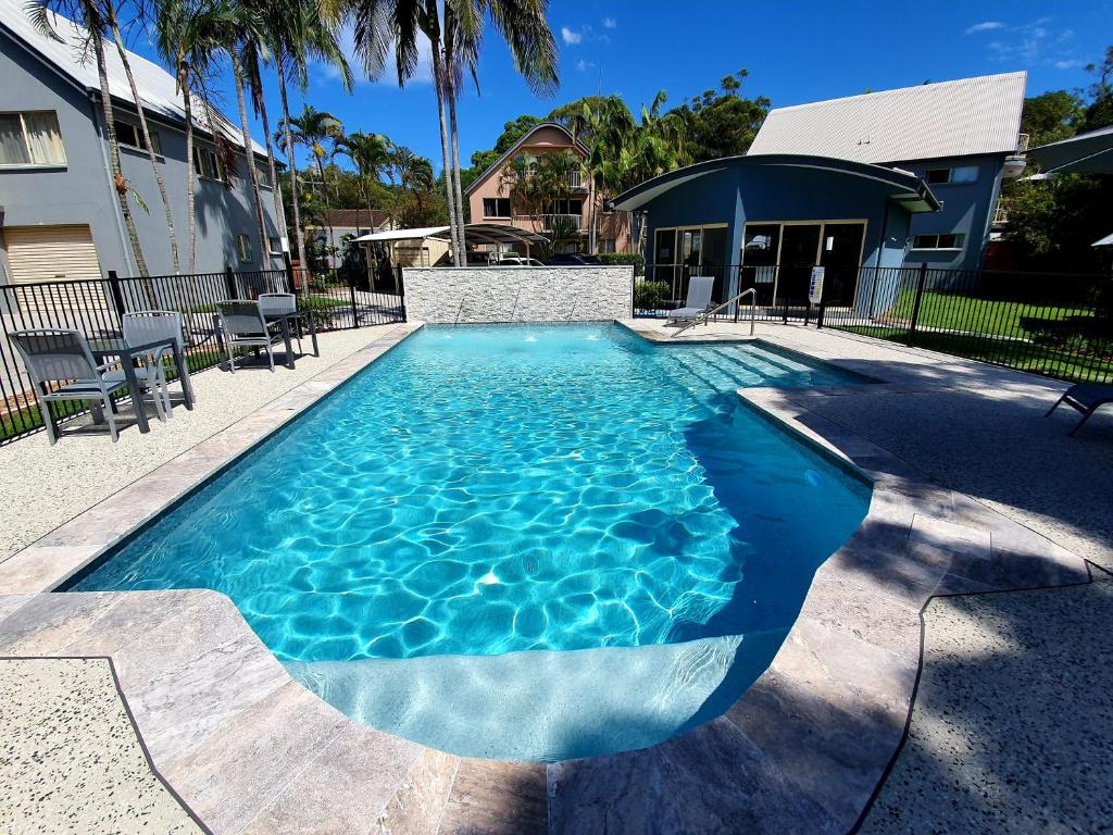 a swimming pool with blue water in front of a house at Rainbow Getaway Holiday Apartments in Rainbow Beach