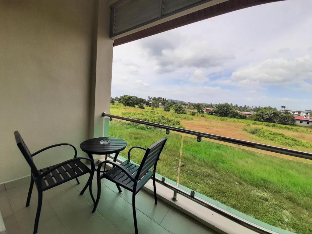 a balcony with a table and chairs and a view of a field at Grand Village Inn in Pantai Cenang