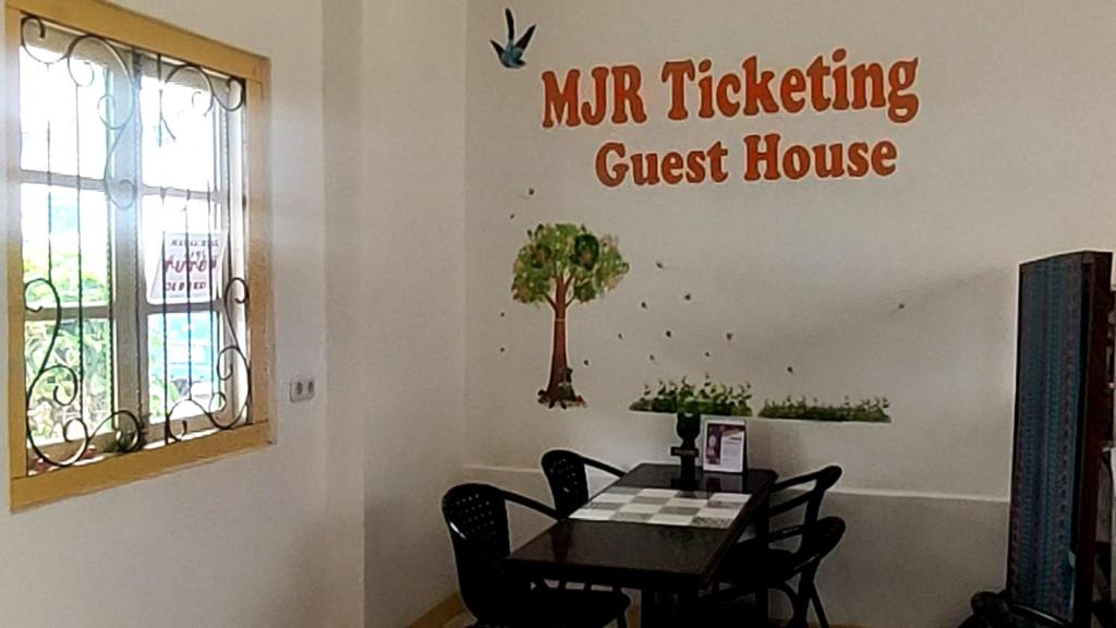 MJR Ticketing Guest House في روتينج: غرفة طعام مع طاولة وعلامة على الحائط