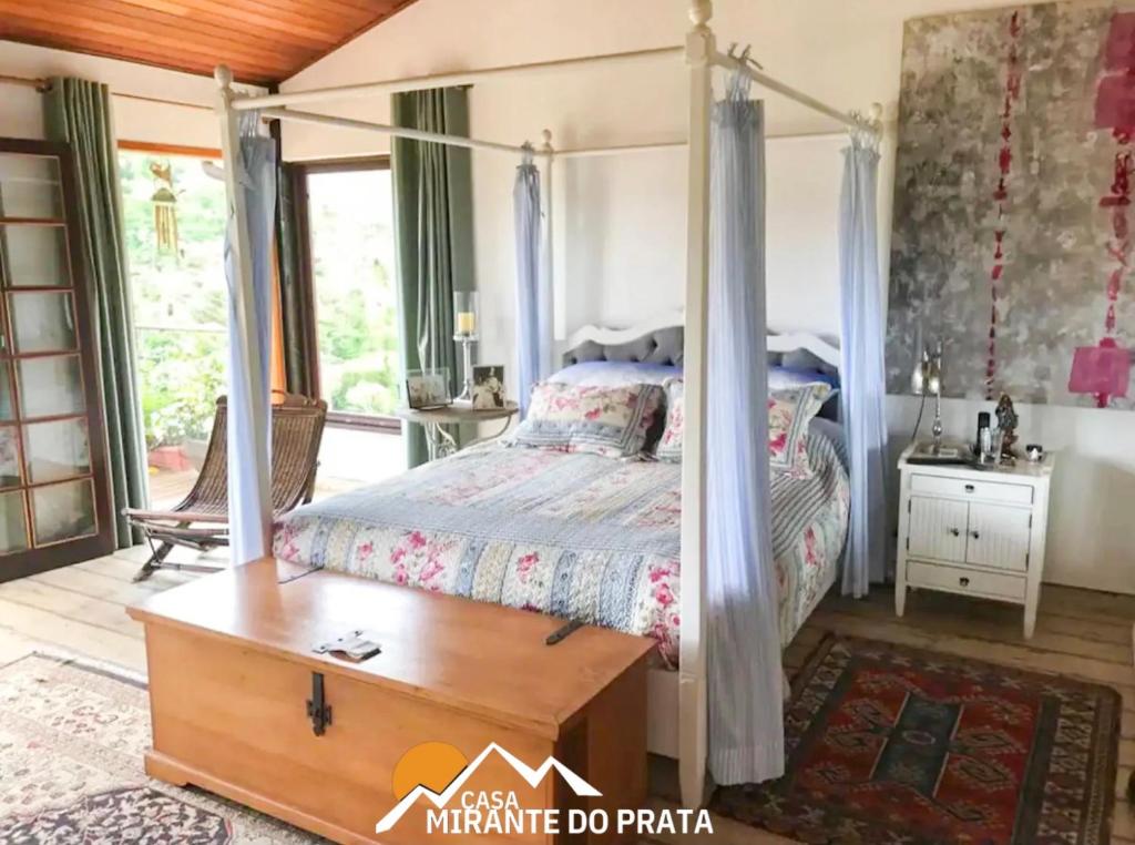ein Schlafzimmer mit einem Himmelbett und einem Tisch in der Unterkunft Casa Mirante do Prata no Vale das Videiras in Araras Petropolis