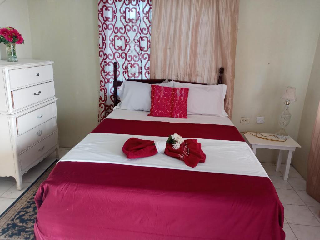 1 dormitorio con 1 cama grande con sábanas rojas y blancas en Royal Villa 360 en Port Antonio