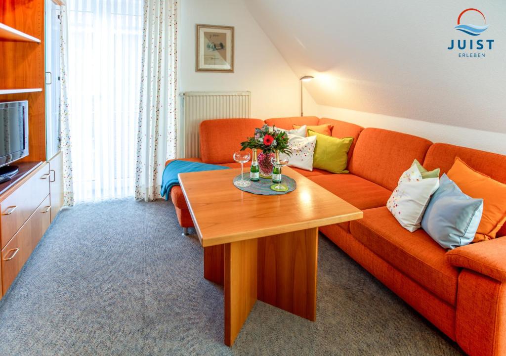 a living room with a orange couch and a table at Haus Petra 133 - Ferienwohnung 3 in Juist