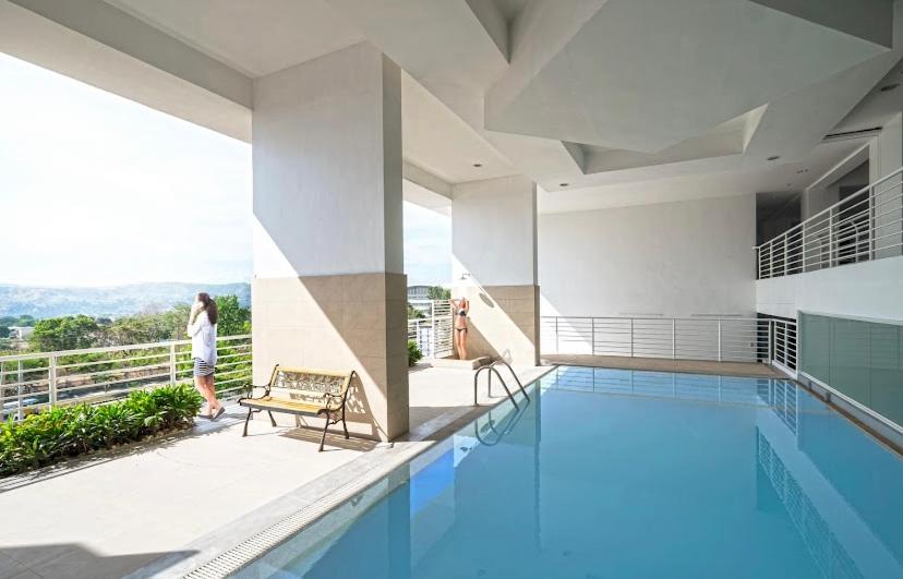 a person standing on a balcony next to a swimming pool at Spacious 2-bedroom condo,Wifi,Netflix,Parking,Pool in Cagayan de Oro