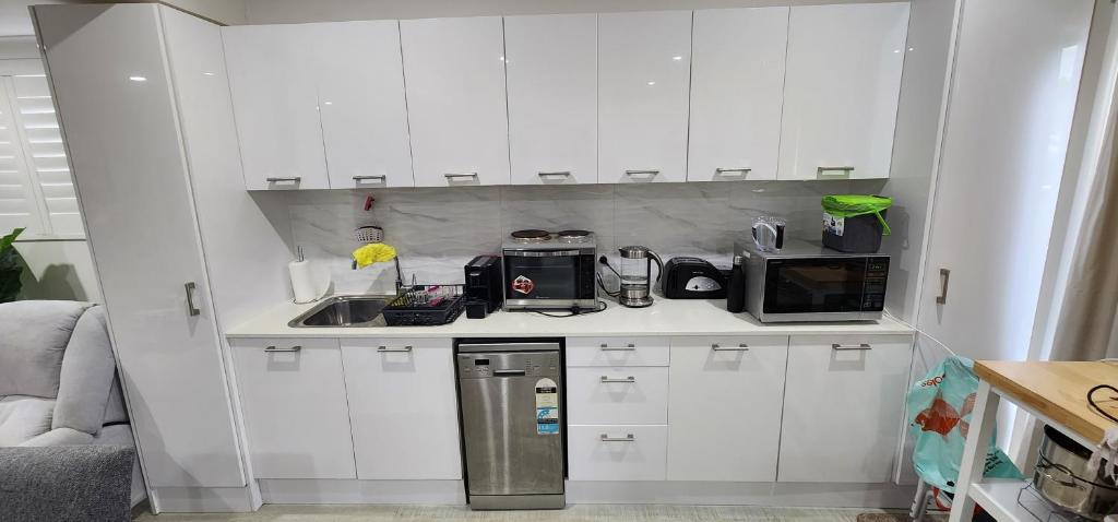 a kitchen with white cabinets and a stainless steel refrigerator at Oscar's at Banora in Kurrara