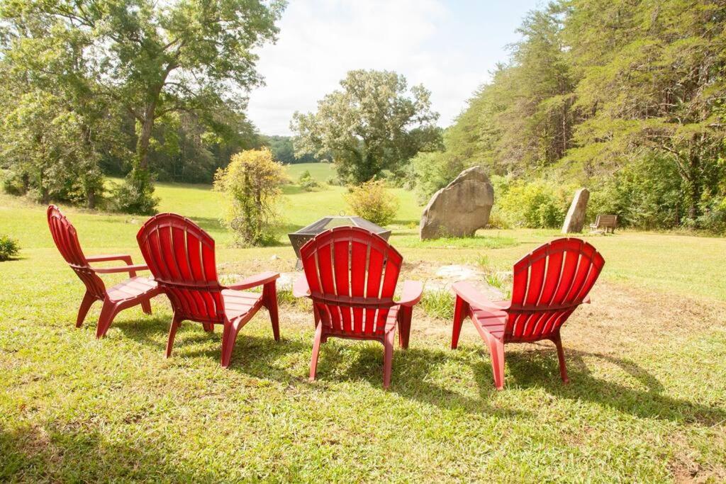 four red chairs and a table in the grass at Home on 30 acres next to State Park in Sampson